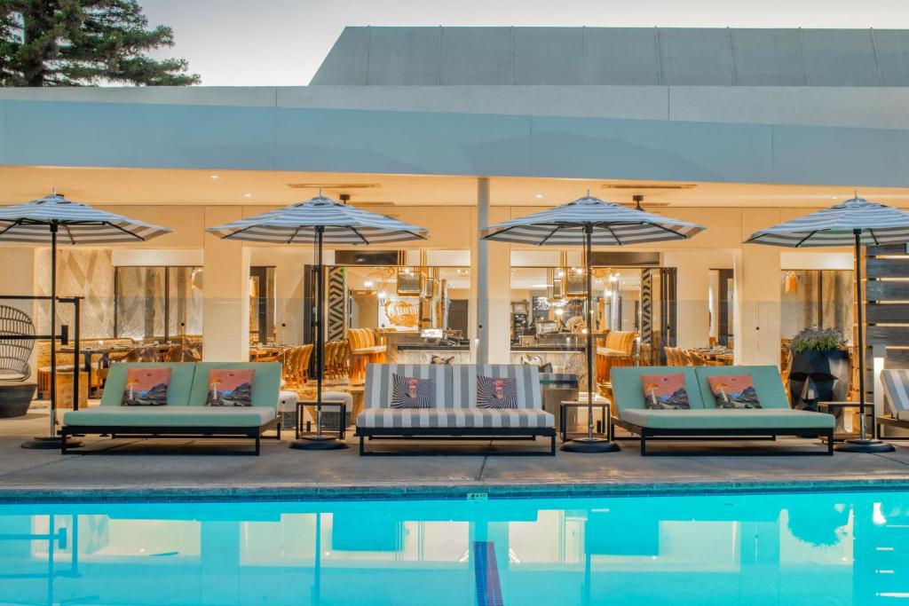 圣克鲁兹帕拉多克斯酒店的一组椅子和遮阳伞,位于游泳池旁