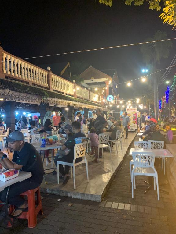 哥打巴鲁Andiana Hotel & Lodge - Kota Bharu City Centre的一群人晚上坐在餐馆的桌子上