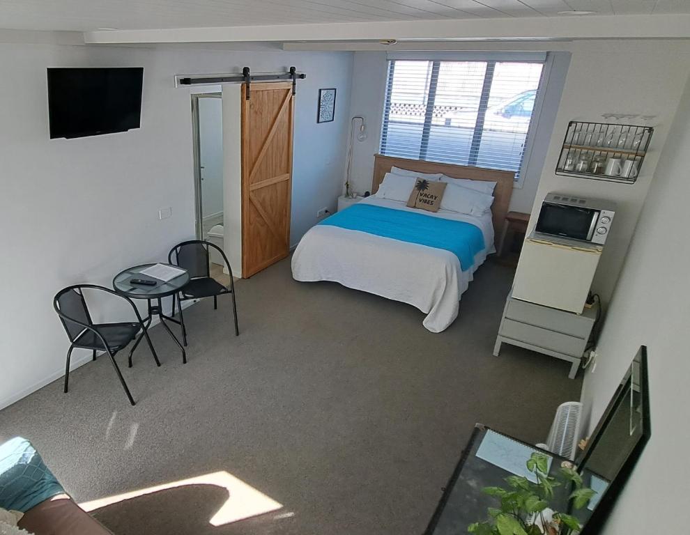 怀蒂昂格Guest Nest in Whitianga - 2 min walk to Beach的一间卧室配有一张床、一张桌子和一台电视。