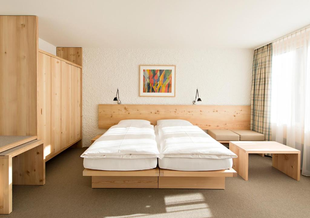 圣莫里茨Hauser Hotel St. Moritz的一间卧室配有一张大床和一张桌子