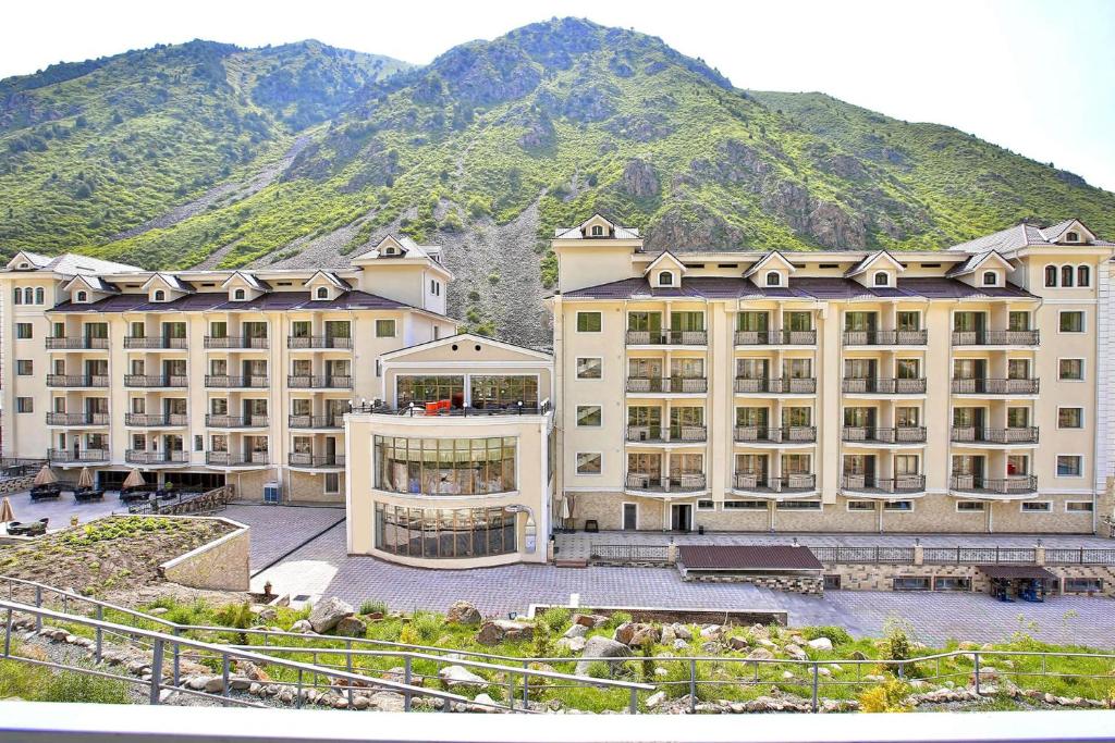 Alamedin詹纳特度假酒店的一座大建筑,背景是一座山
