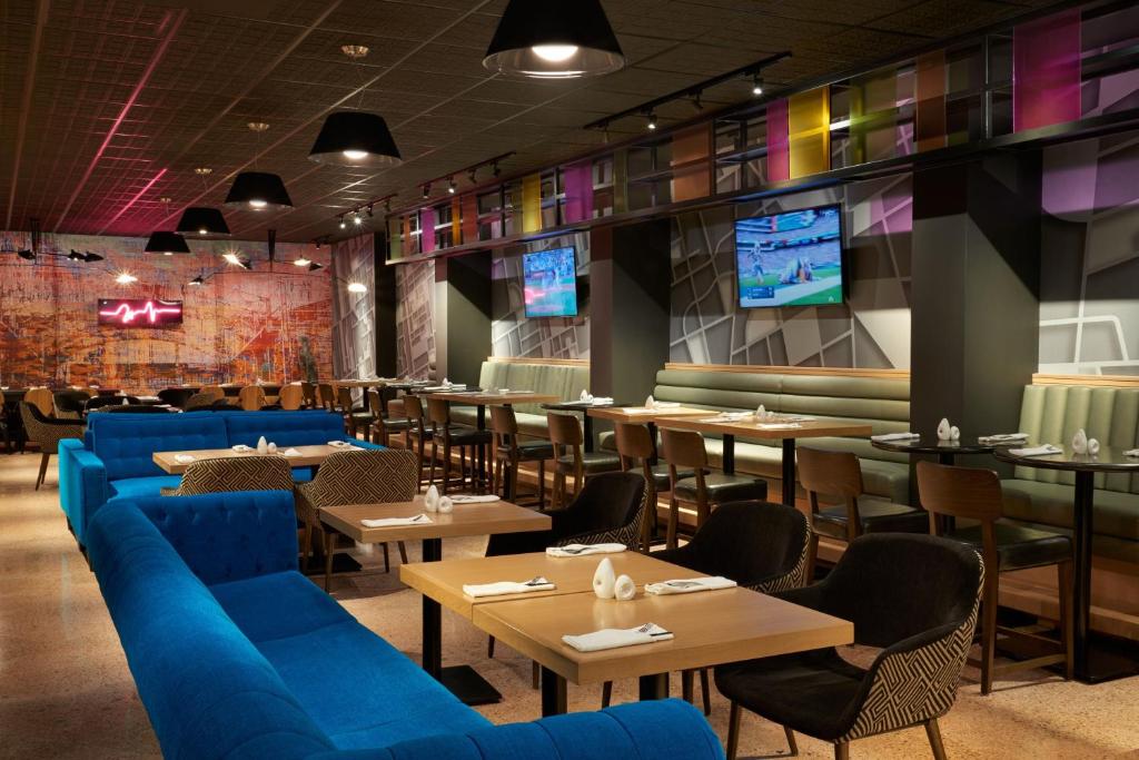 多伦多多伦多机场和会议中心万豪德尔塔酒店的餐厅设有蓝色的沙发、桌子和电视