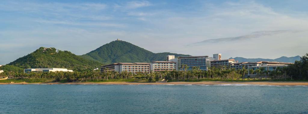 三亚三亚天丽湾凯悦酒店的一群在海滩上以山脉为背景的建筑