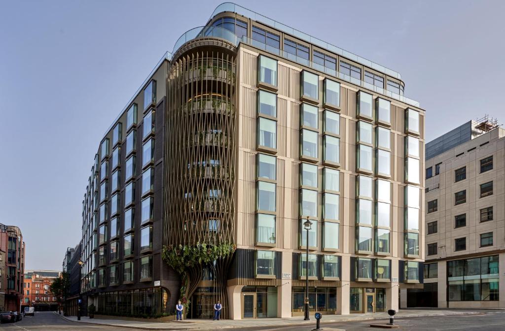 伦敦The BoTree - Preferred Hotels and Resorts的一座大型玻璃建筑,前面有一棵树