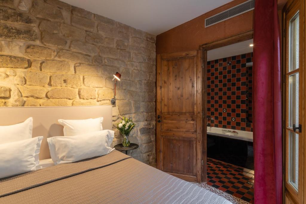 巴黎Hôtel Prince de Conti的一间卧室设有一张床和石墙