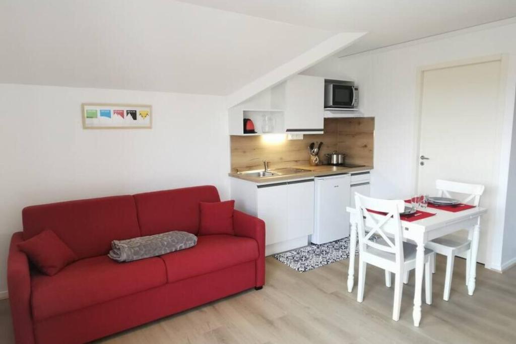 莱代塞尔Studio 2 pers avec accès piscine et sauna的一间带红色沙发的客厅和一间厨房