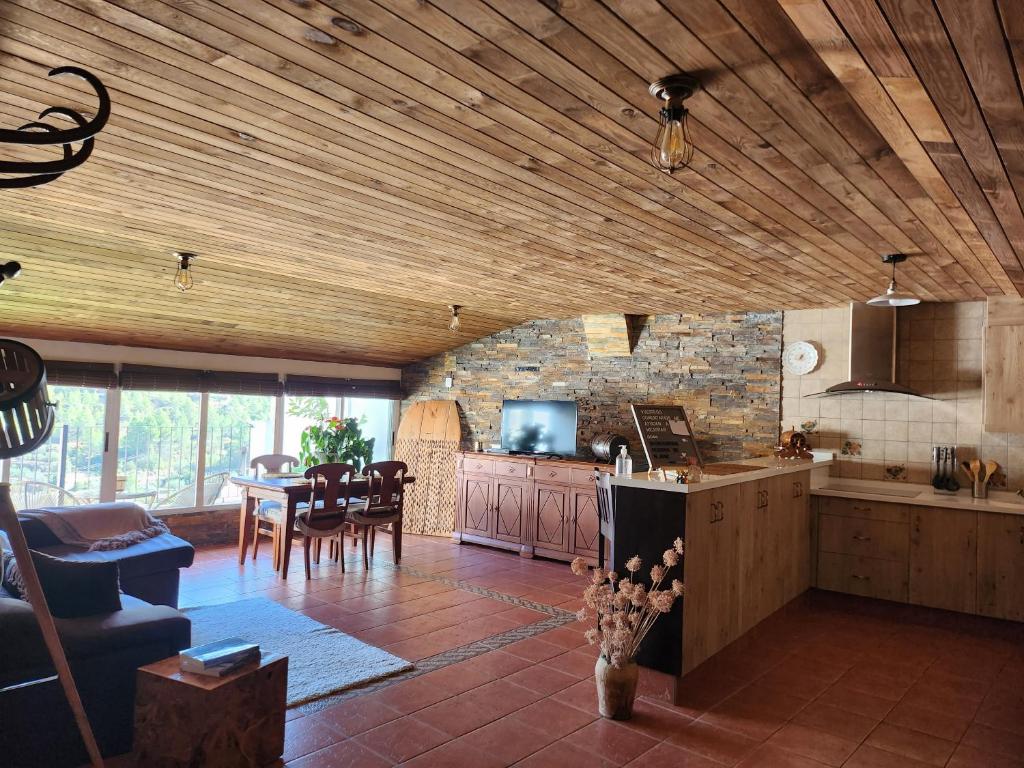 比利亚埃尔莫萨德尔里奥Buhardilla rústica muy acogedora的一间厨房和带木制天花板及桌子的用餐室