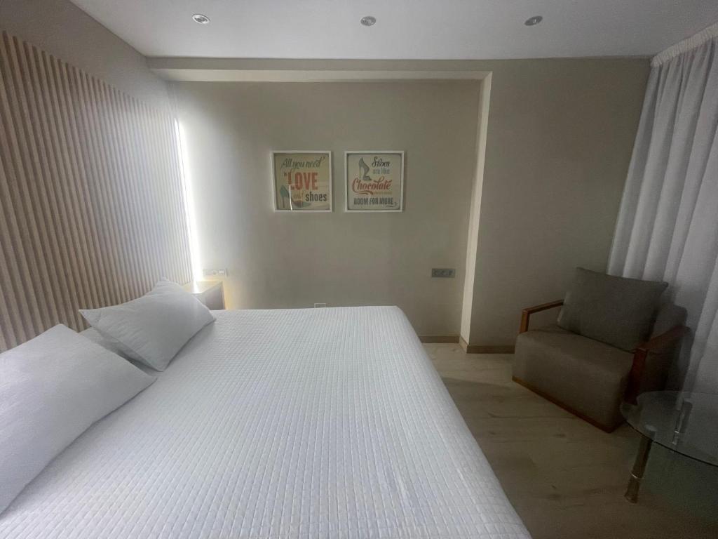 克辛索德利米亚Hotel orly的卧室配有一张白色大床和一把椅子