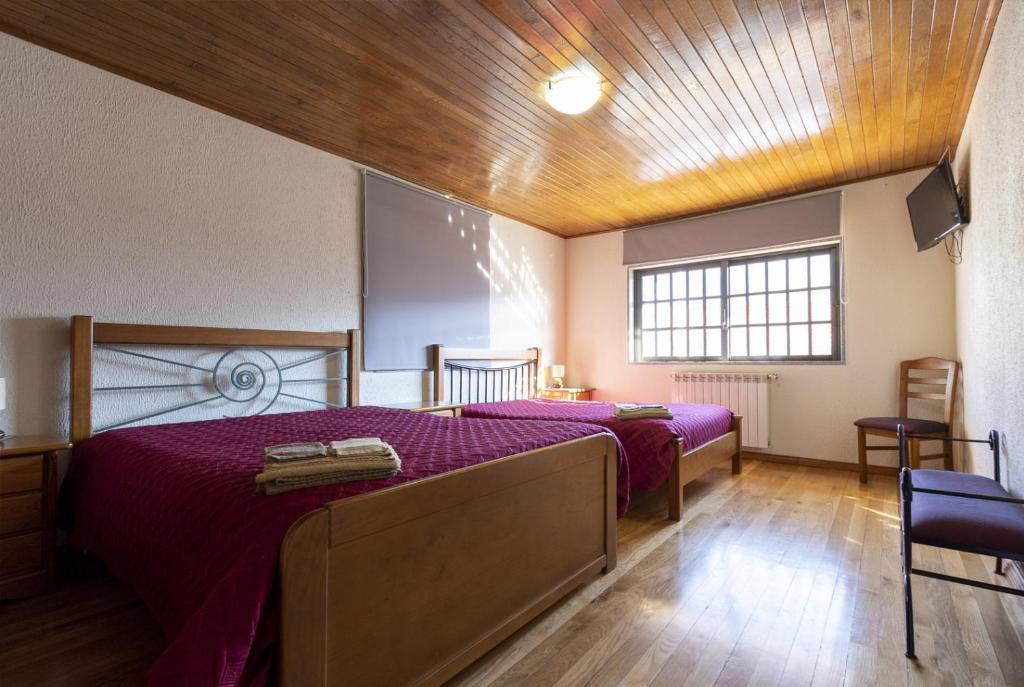 萨布盖鲁Casa do Patrão - Quartos的一间卧室设有两张带紫色床单的床和木制天花板。