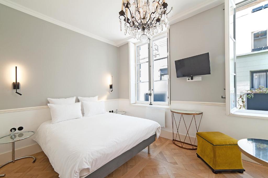 巴黎Pavillon Marais的卧室配有白色的床和吊灯。