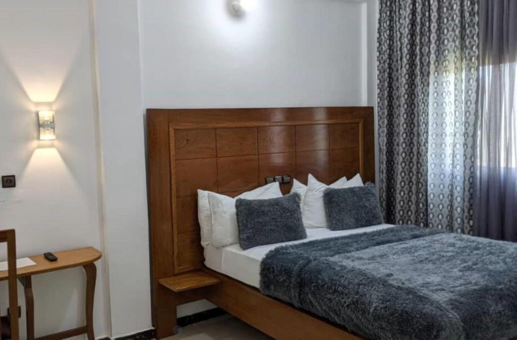 DschangJAD HOTEL Dschang的一间卧室配有一张带木制床头板的床