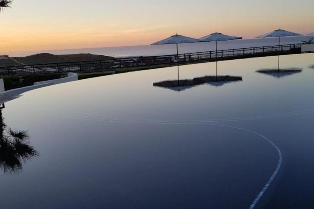 卡波圣卢卡斯Exquisite 3BR Condo Ocean Views Access Resorts的海滩上带遮阳伞的大型游泳池