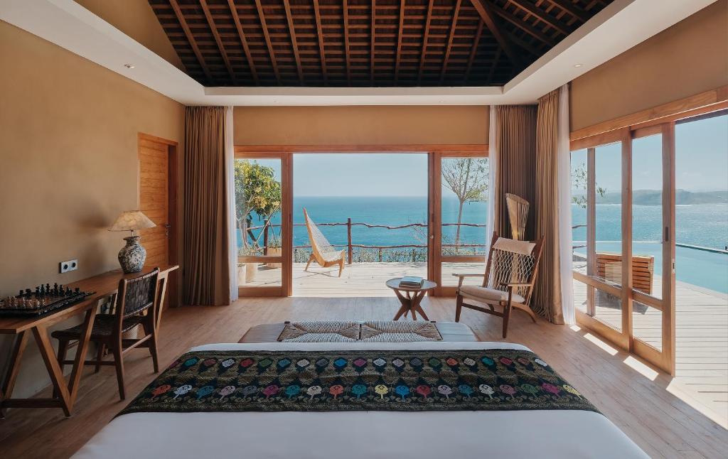 BumbangTUNAK Resort Lombok的一间卧室设有一张床和一张书桌,享有海景