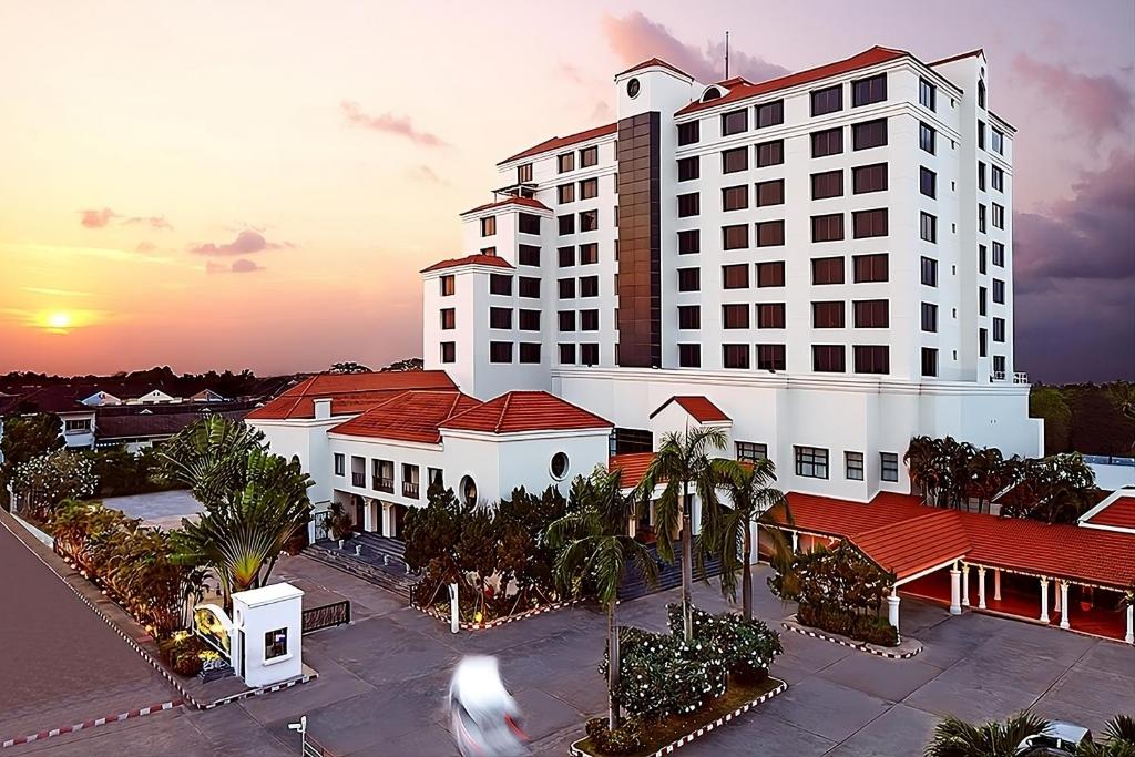 Ban Ru Sa Mi Laeโรงแรม ซี.เอส. ปัตตานี的一座白色的大建筑,前面有棕榈树