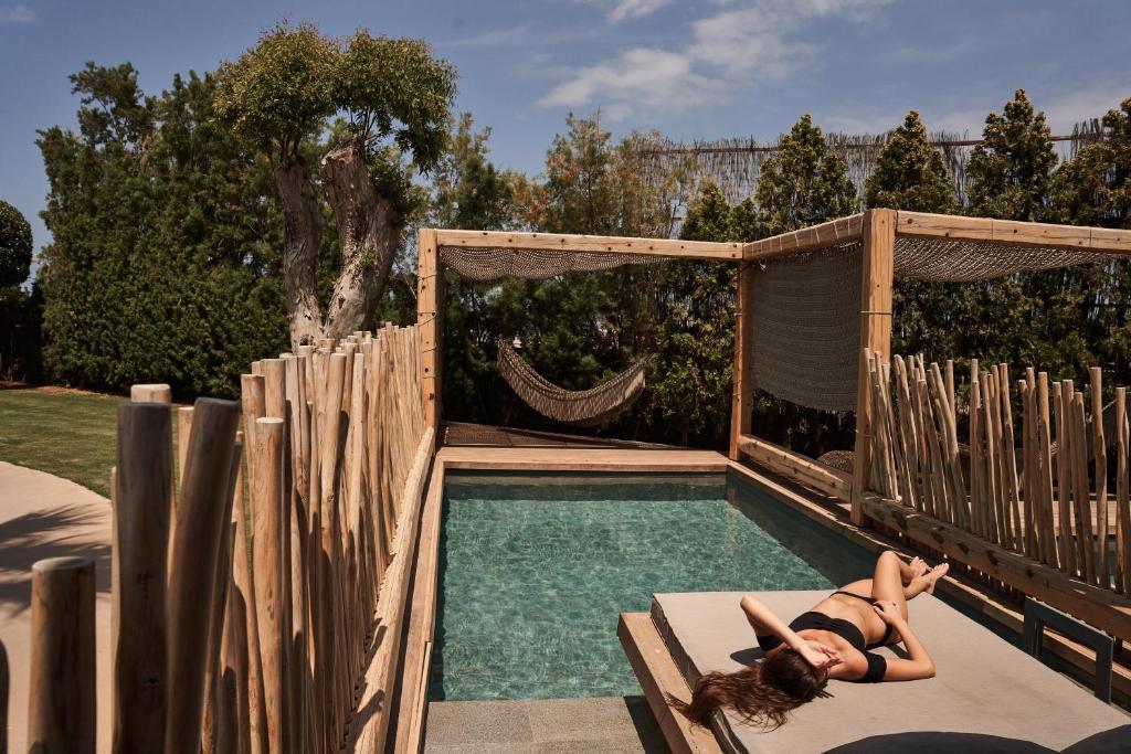 赫索尼索斯NEMA Design Hotel & Spa - Adults Only的躺在游泳池旁长凳上的女人