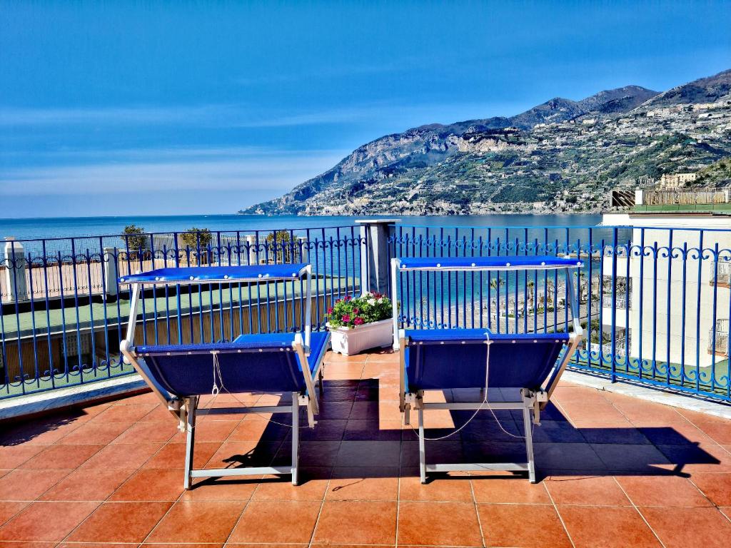 马奥莱A terrace on the sea的两把蓝色椅子坐在一个俯瞰着大海的阳台