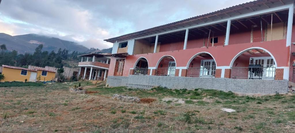 卡哈马卡Casa de campo completa a 20 minutos de Cajamarca Aire puro fogata y mas的山丘上带窗户的粉红色建筑