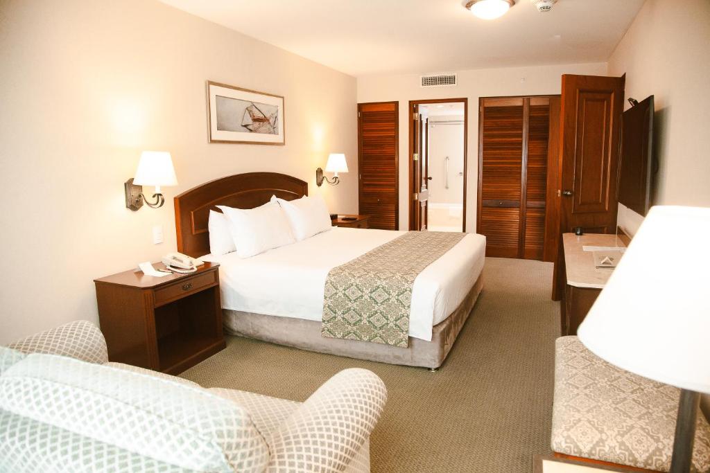 利马Los Tallanes Hotel & Suites的酒店客房,配有一张床和两把椅子