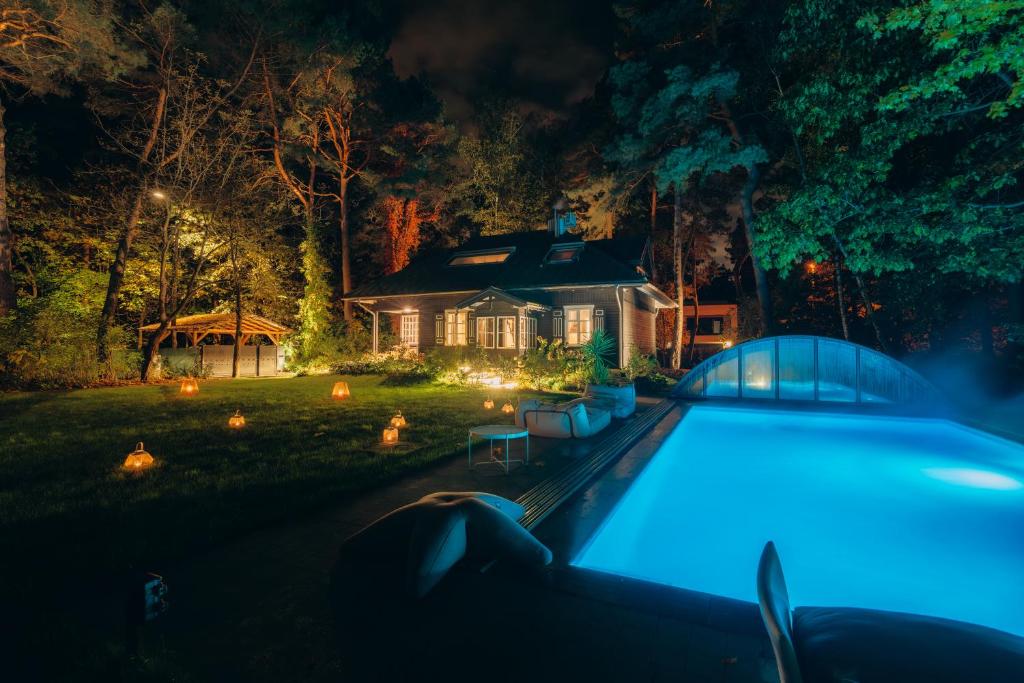华沙Joy Village的一座晚上设有游泳池的房子