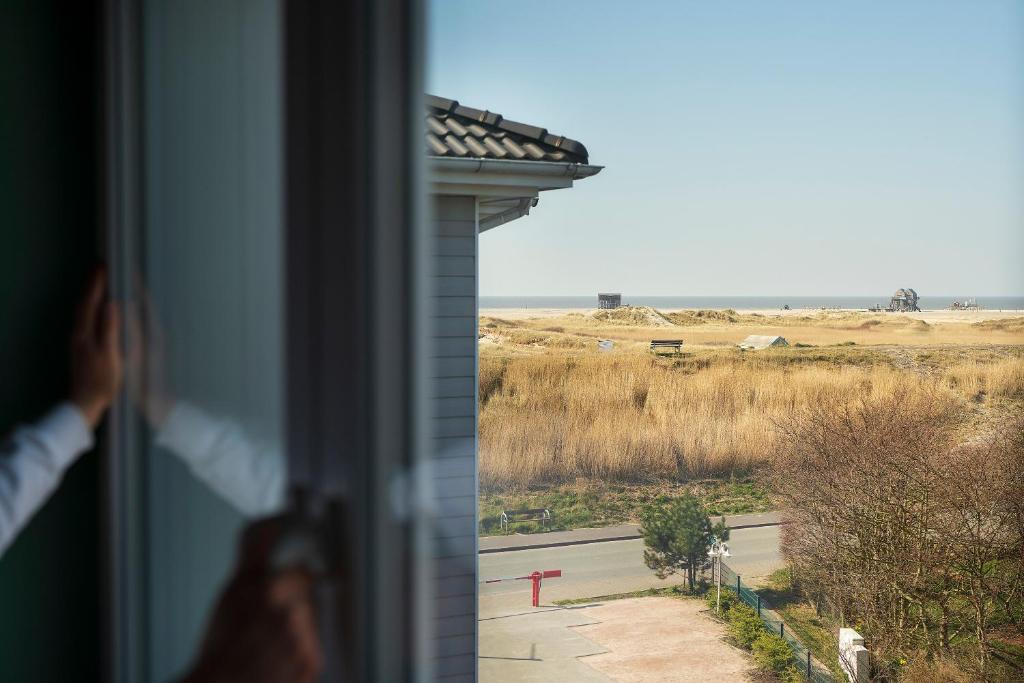 圣彼得奥尔丁Beach Motel St. Peter-Ording的看到田野窗户的人