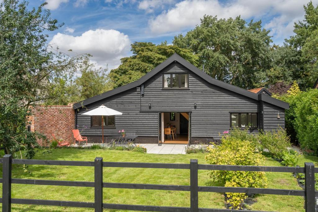 哈勒斯登Contemporary Barn Waveney Valley的前面有栅栏的黑色房子