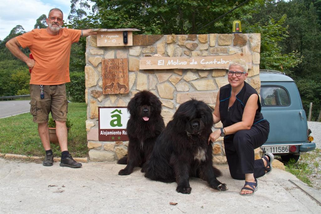 EntrambasaguasPosada Pet Friendly El Molino de Cantabria的坐在两只黑狗旁边的一个男人和一个女人