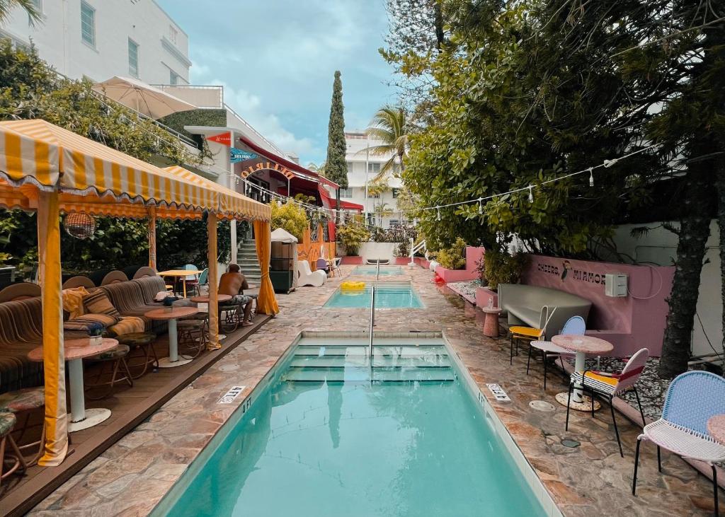 迈阿密海滩Viajero Miami的一座带桌椅的游泳池位于酒店大楼旁