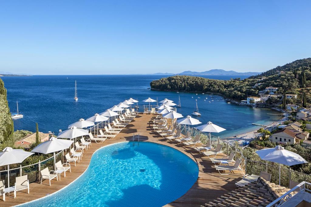 卡拉米San Antonio Corfu Resort (Adults Only)的一个带遮阳伞和椅子的游泳池以及一个海滩