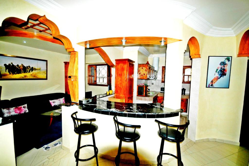 杰迪代Appartement Vintage à EL JADIDA rte Sidi Bouzid的一个带四把酒吧凳子的小岛的厨房