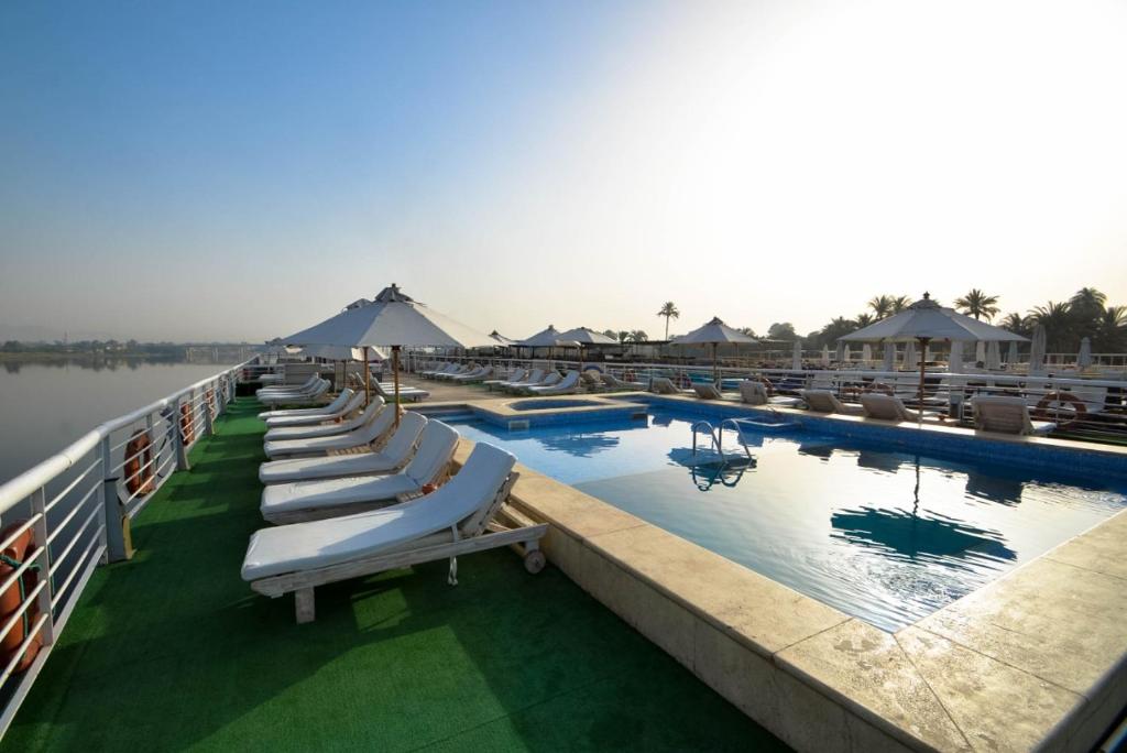 卢克索Nefertari Nile Cruise From Luxor 4&7 Nights, Every Saturday, Monday And Thursday Including tours的度假村游泳池里一排躺椅
