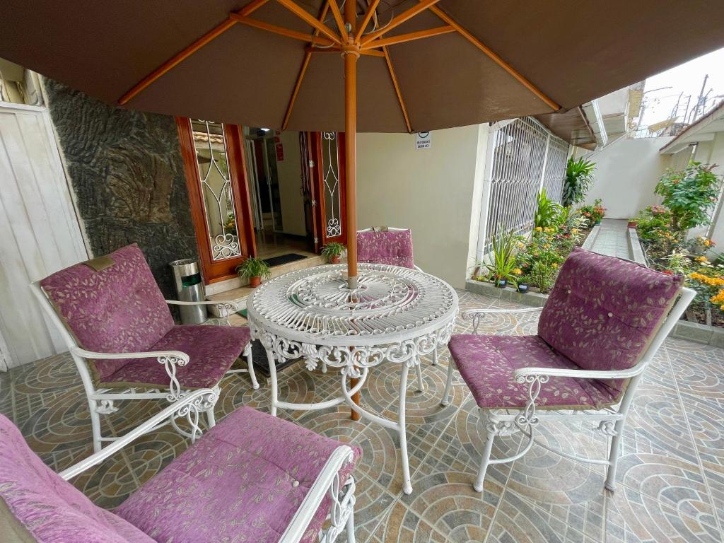 瓜亚基尔加尔萨别墅旅馆的庭院里配有一张带紫色椅子的桌子和一把遮阳伞
