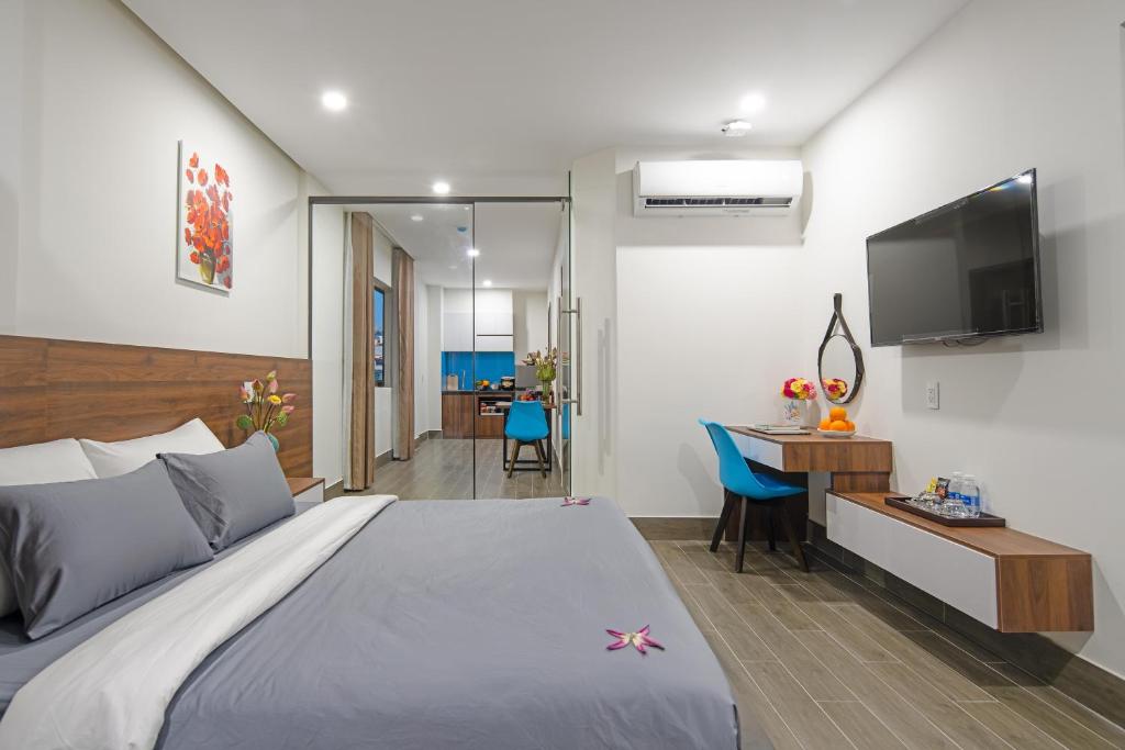 岘港TIDITEL Hotel and Apartment的一间卧室配有一张床、一张书桌和一台电视