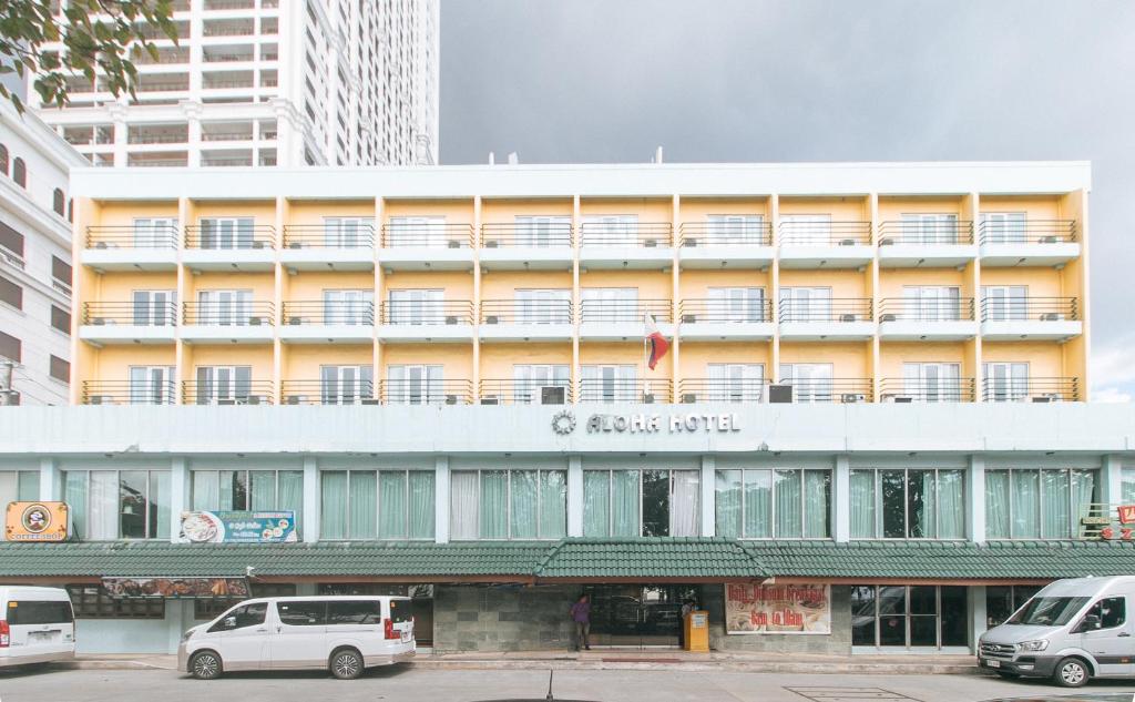 马尼拉Aloha Hotel Roxas Boulevard Manila的前面有汽车停放的建筑