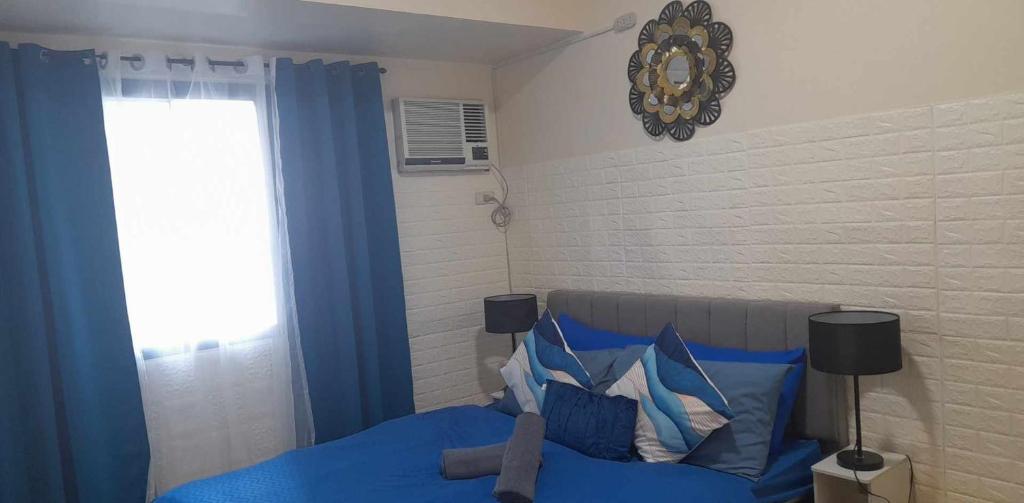 马尼拉US Embassy Roxas Blvd, Ermita, Manila 1 Bedroom ComfySuite的一间卧室设有蓝色的床和窗户。