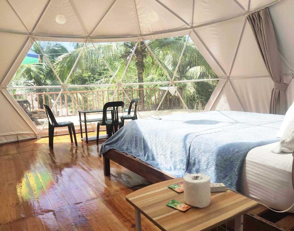 BalilihanEco Glamping Treehouses Closest Resort To All Tourist Attractions的帐篷内带一张床和一张桌子的房间