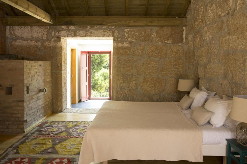 维拉·雷阿尔Casa Agricola da Levada Eco Village的卧室配有一张石墙床