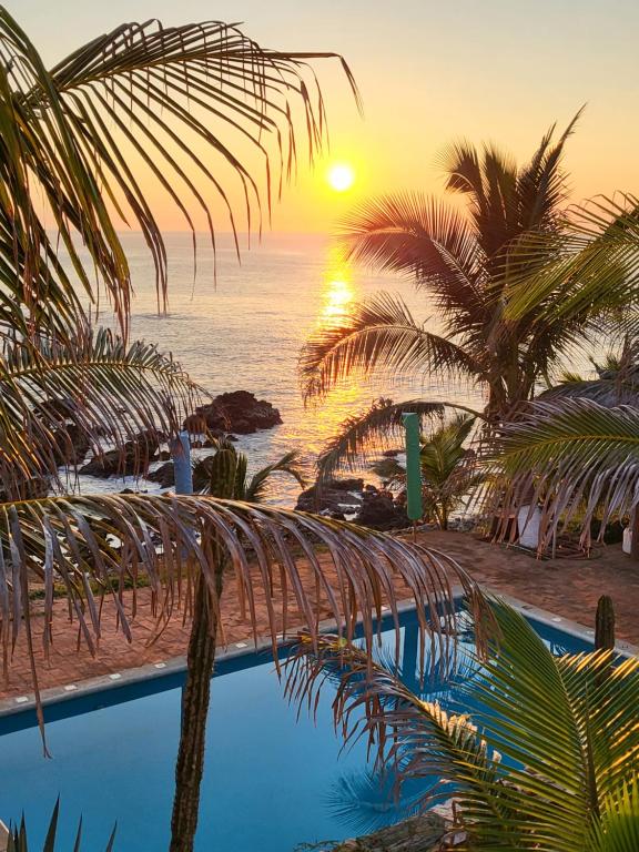 CuatunalcoHotel Luz de Mar ' right on the beach的棕榈树和游泳池的日落