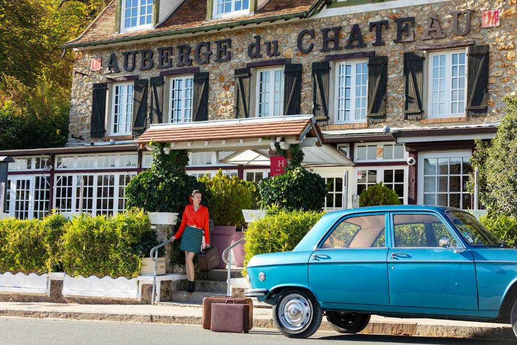 DampierreL’Auberge du Château的站在一座蓝色汽车的建筑前面的女人