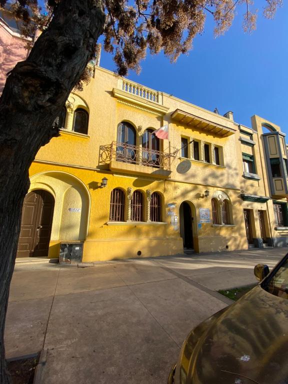 圣地亚哥Hostal El Raco的街道上带阳台的黄色建筑