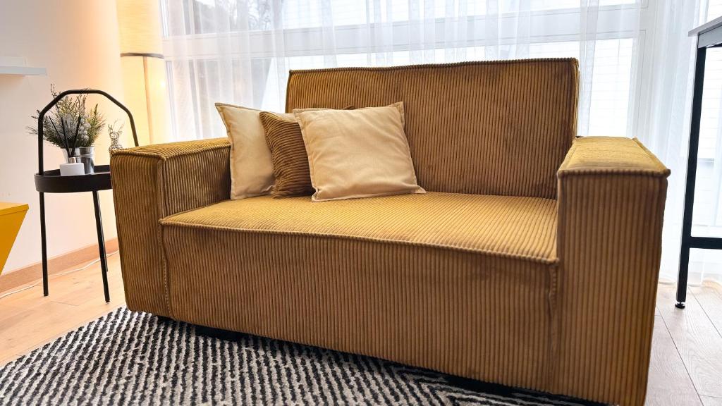 帕兰加Vytauto 80的客厅配有带两个枕头的棕色椅子