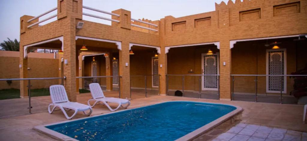 Al Khabrāʼشاليه غرناطة的一座带游泳池和两把椅子的房子