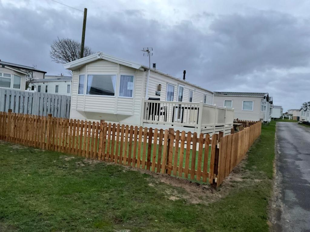 布里恩2 Brightholme 6 berth with Decking & enclosed gard的木制围栏后面的白色房子