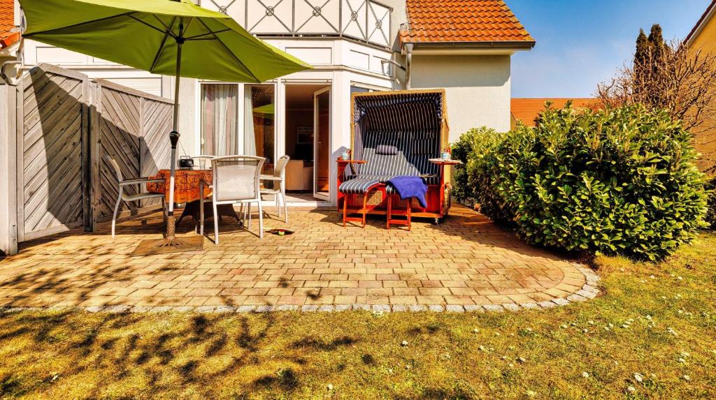 奥斯赛拜-屈隆斯博恩Ferienanlage-Reriker-Strasse-Ostseehus-717的庭院配有桌椅和遮阳伞。