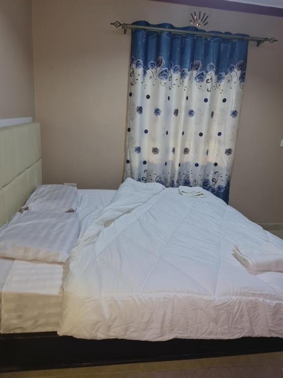 SiayaChrista's haven的卧室配有白色床和蓝色窗帘
