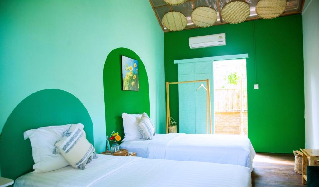 Hiếu XươngLumiere Family Village Dong Tac的配有两张床铺的绿色和蓝色墙壁客房