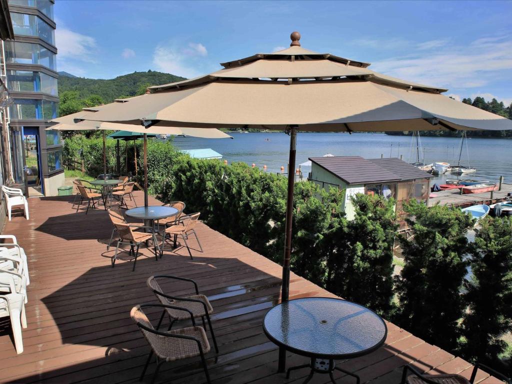 信浓野尻湖度假酒店的一个带桌椅和遮阳伞的庭院
