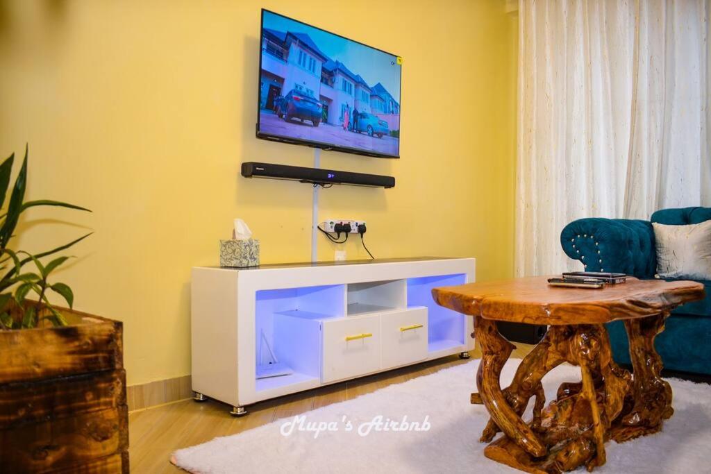 NyahururuMupa's Luxury Condo II的客厅配有桌子,墙上配有电视