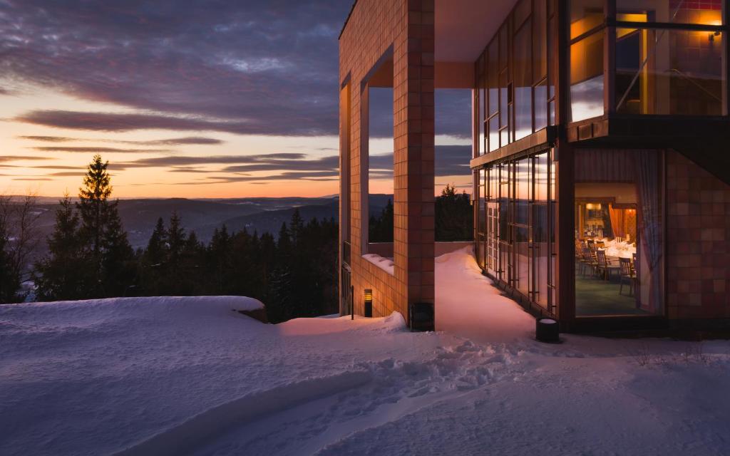 奥斯陆索里亚莫里亚酒店的雪中一座建筑,背景是日落