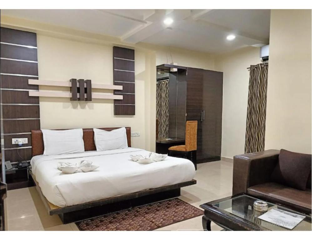 占西Hotel Bundelkhand Pride, Jhansi的一间卧室配有一张床、一张沙发和一张桌子