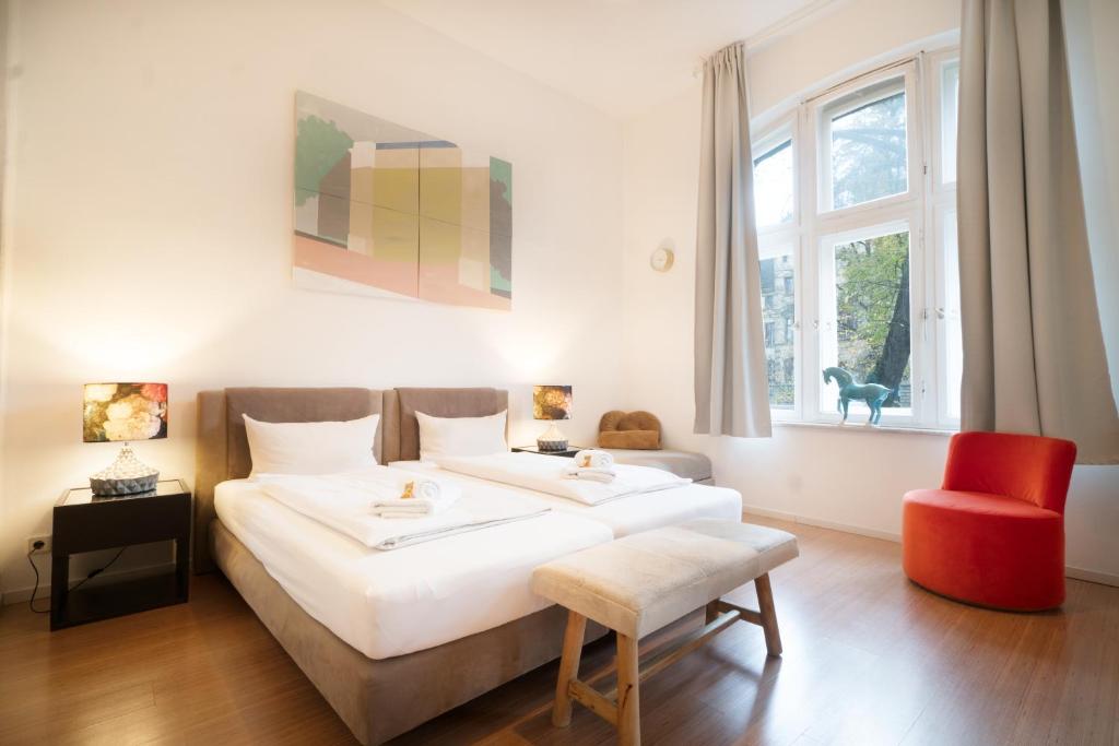 奥斯纳布吕克Heger Tor Apartments的卧室配有一张白色大床和红色椅子